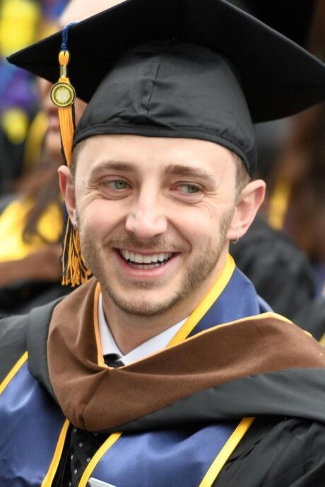 Man in graduation cap and gown smiling