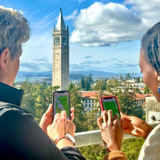 Two people looking at maps on their phones with Campanile in background